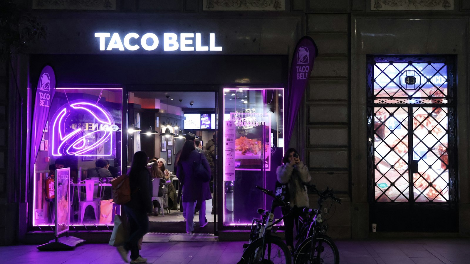 A brightly lit shopfront with people walking past