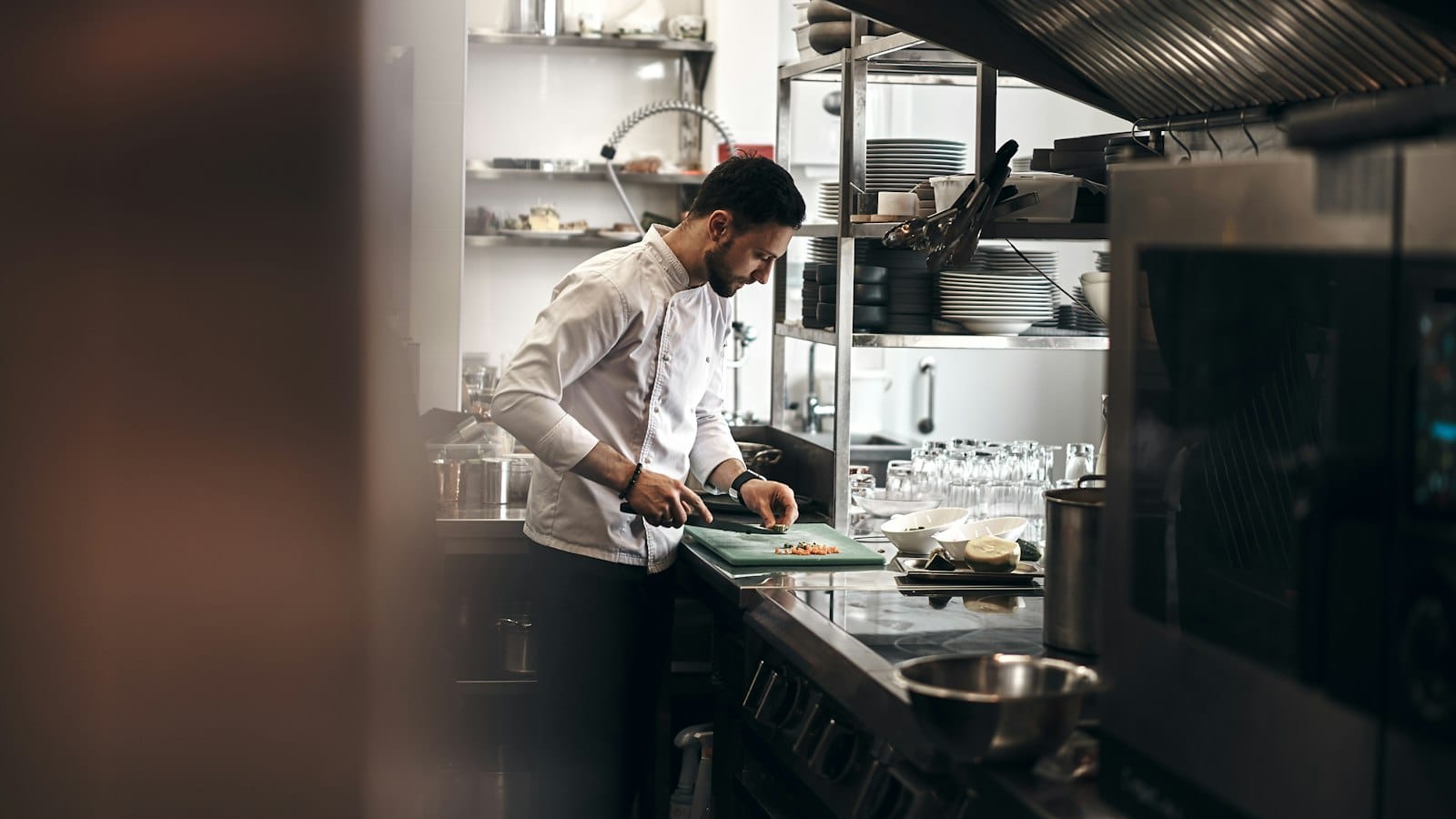 A chef in a white jacket working in a restaurant kitchen