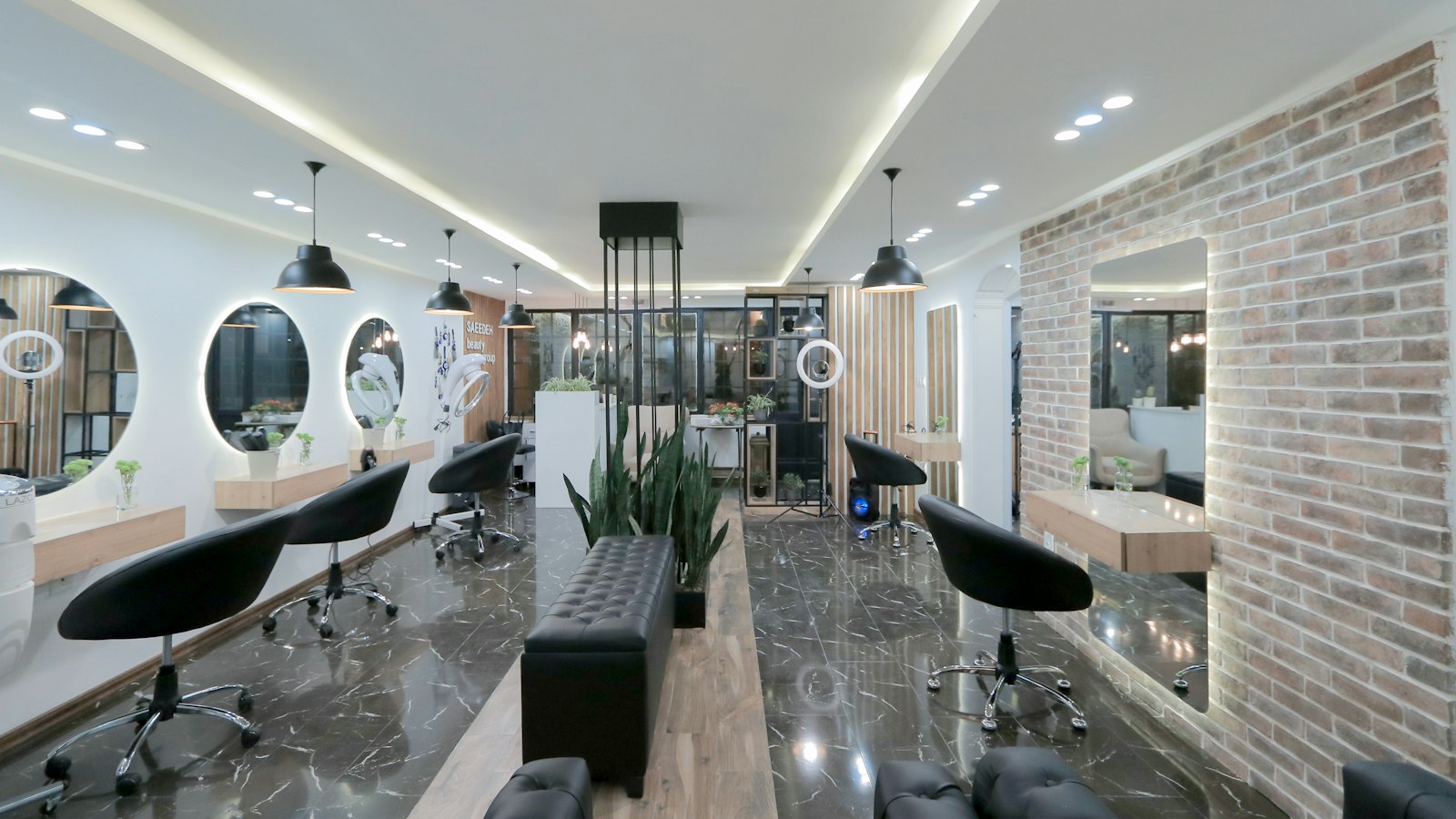A hair salon with black chairs and round mirrors against a brick wall