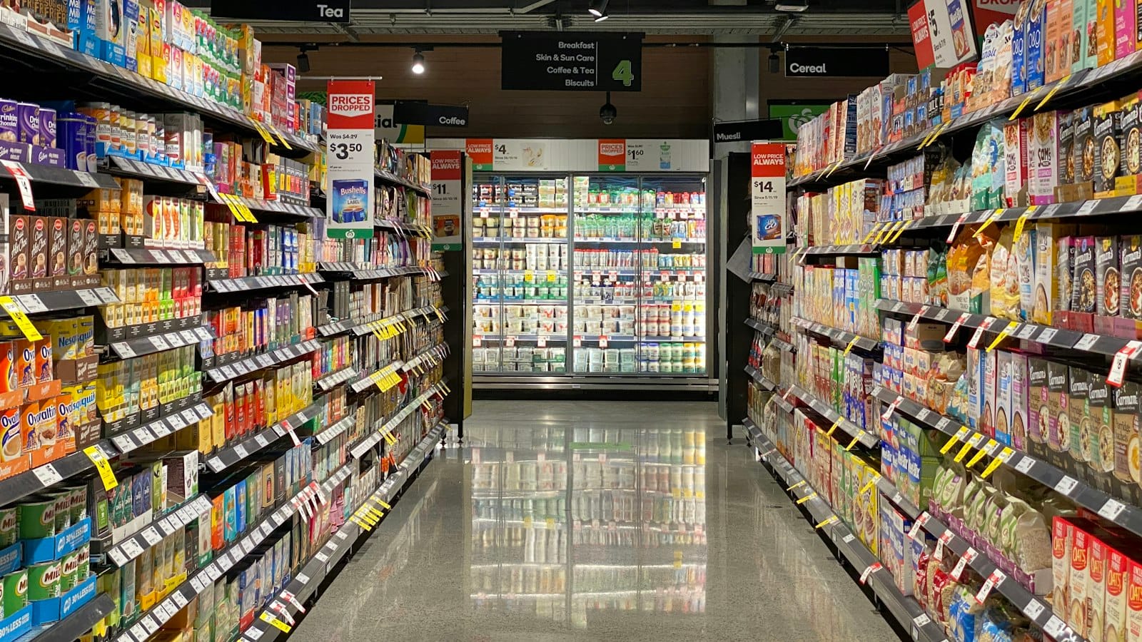 A shop aisle with shelves and chilled food cabinets