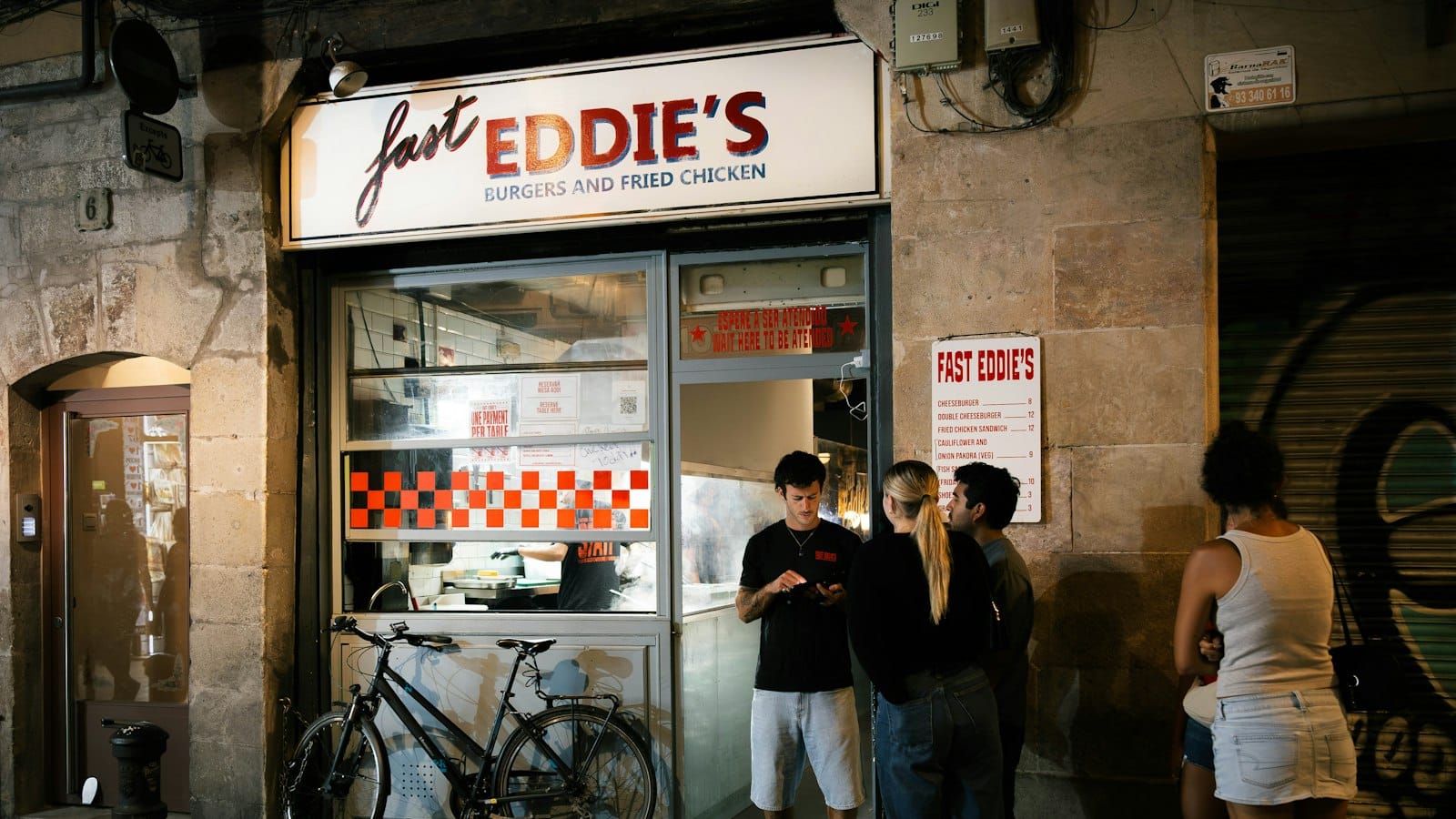 Customers waiting outside a small late-night takeaway