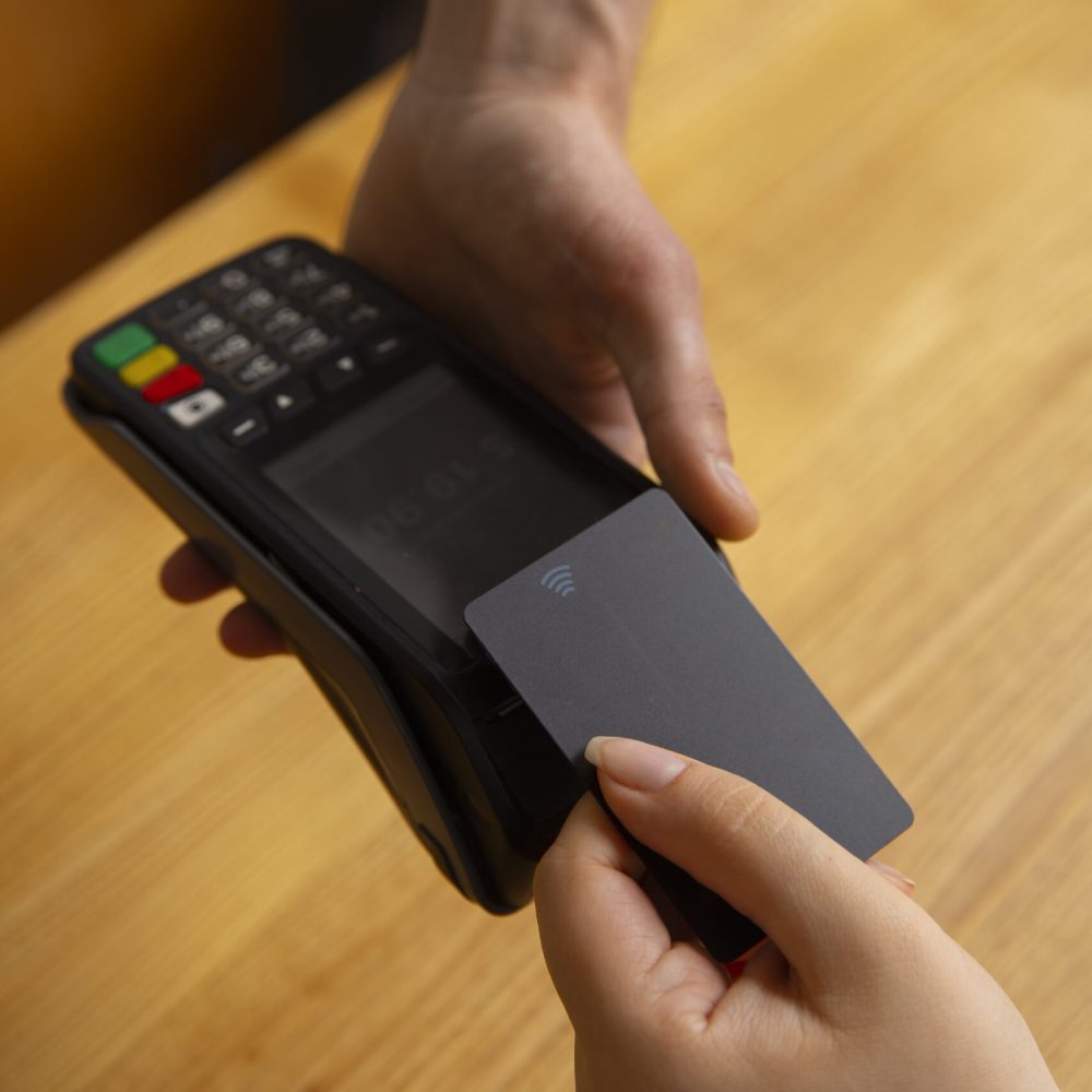 high-angle-customer-paying-with-nfc-device-scaled